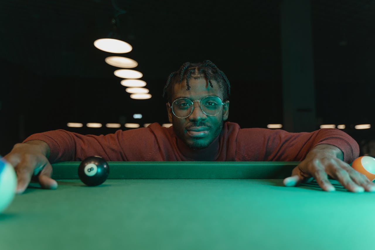 Close-Up Shot of a Man With Eye Glasses Leaning on a Billiard Table